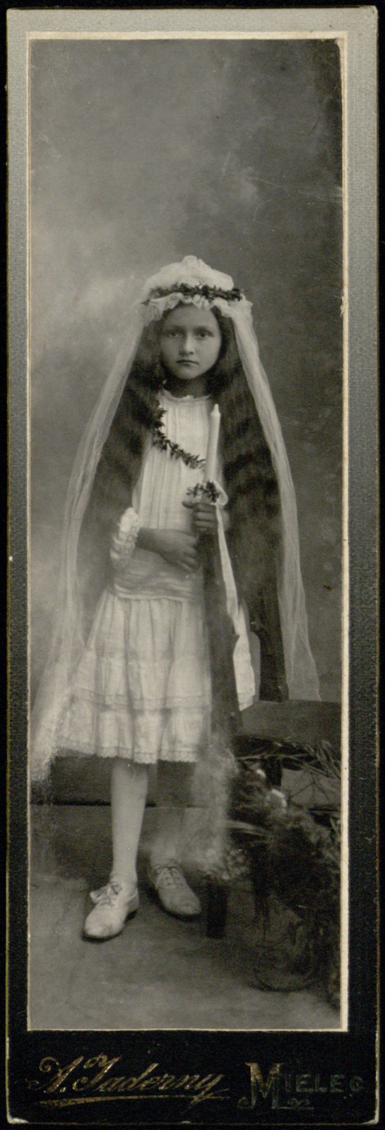 dziewczynka w stroju komunijnym z długim welonem
